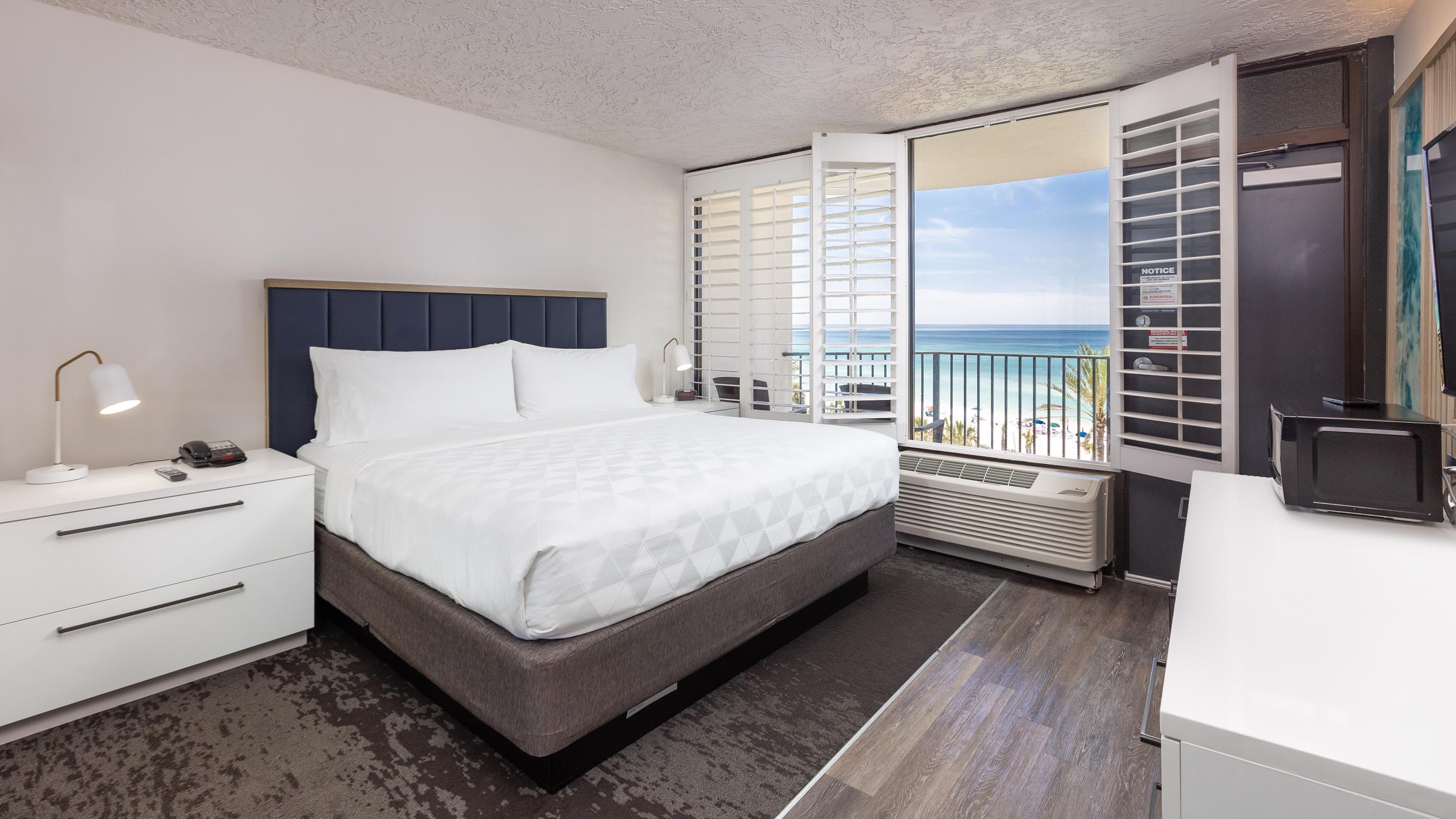 King bed with white side table and view of balcony and ocean